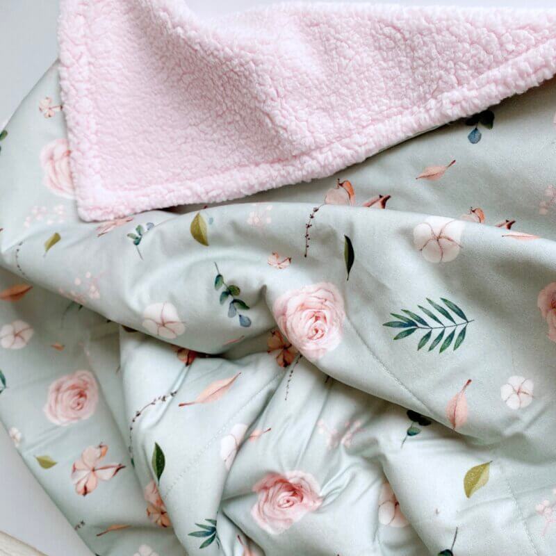 Couverture pour bébé aux motifs de roses turquoise en satin de coton avec doublure sherpa rose fabriquée au Québec par La Fée.